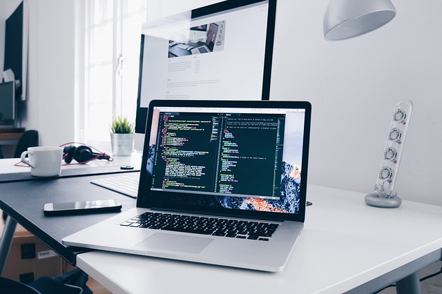 Laptop on a white desk with code on the screen