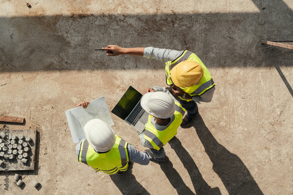 Project team reviewing plans on a laptop at a construction site